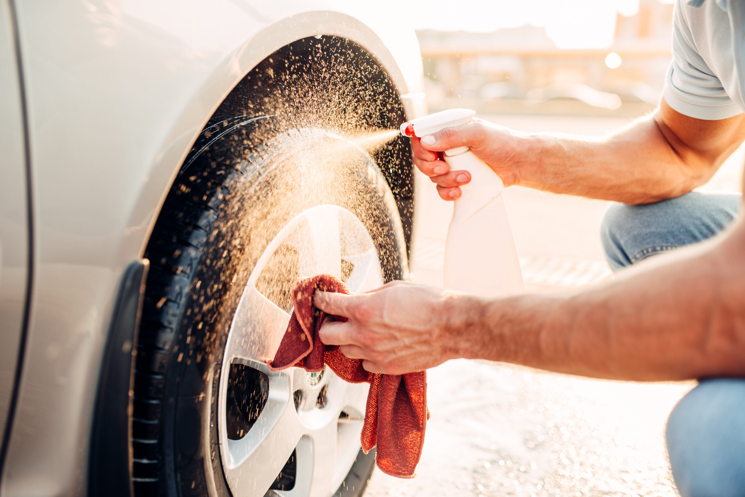 Person cleaning vehicle wheel and tire during spring car detailing in Kingsville